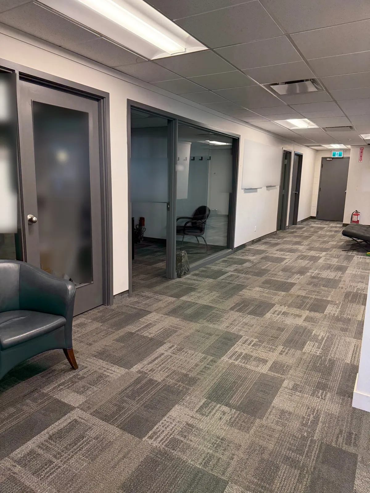 Bright office hallway with glass-front offices and freshly vacuumed carpet tile after a Celestial office clean