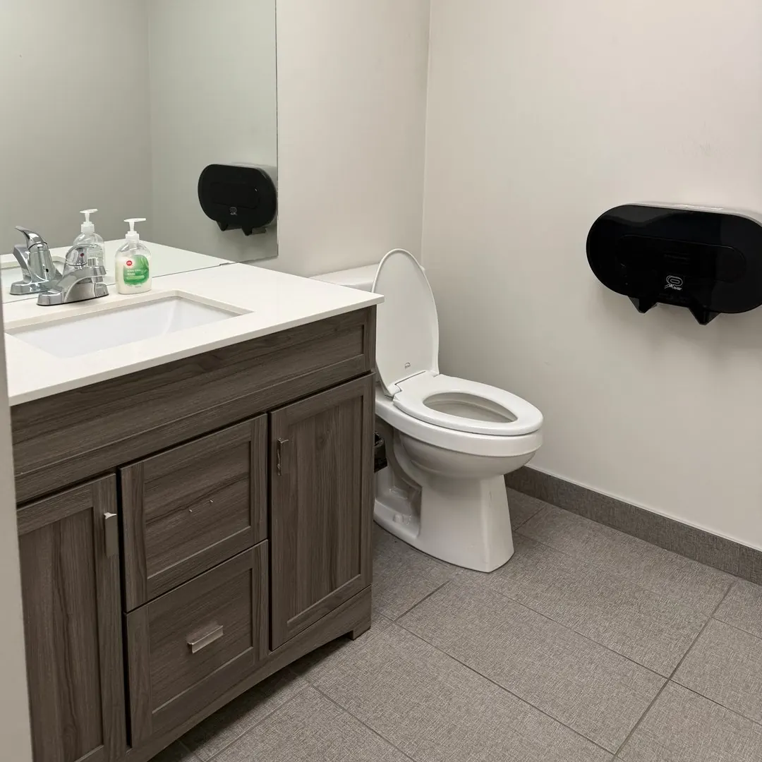 Clean office washroom with a wood vanity, white sink and mirror after a Celestial office clean